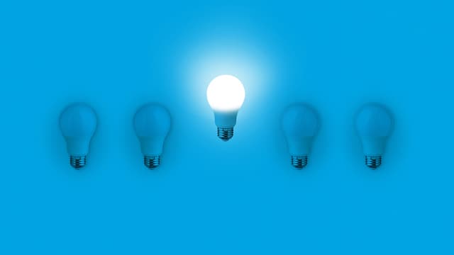 Blue light bulbs with glowing one different idea on blue background. minimal concept. top view. New Creative Idea